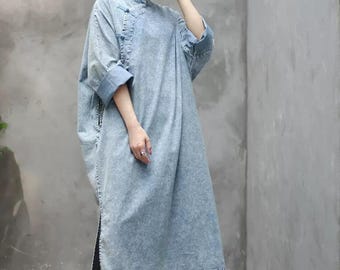 May include: A light blue denim dress with a mandarin collar and a side button closure. The dress has a relaxed fit and a long, flowing silhouette.