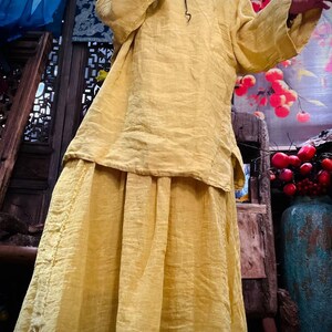 May include: A yellow linen tunic top and skirt set. The top has a mandarin collar and long sleeves. The skirt is a-line and falls to the ankles.