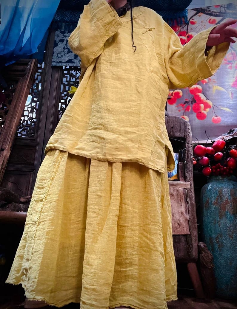 May include: A yellow linen tunic top and skirt set. The top has a mandarin collar and long sleeves. The skirt is a-line and falls to the ankles.