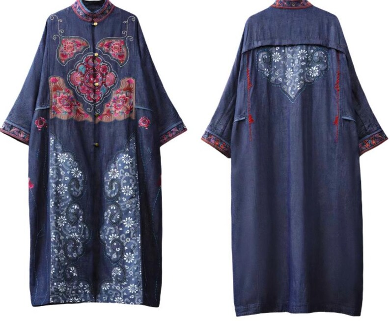 May include: A long, dark blue denim dress with intricate floral embroidery in pink, red, and white. The dress features a mandarin collar, button closures, and a unique embroidered design on the back. The sleeves and hem are detailed with patterned trim.