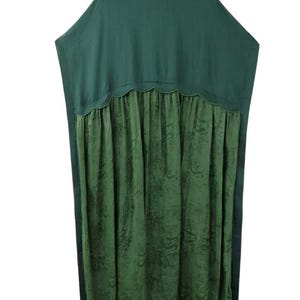 May include: A loose-fitting tunic in two shades of green. The upper section is a solid dark forest green with a smooth texture, while the lower section is a lighter olive green with a subtle, tonal floral pattern, joined by a scalloped seam.