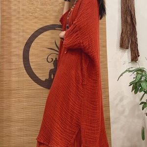 May include: A long, loose-fitting, red linen dress with a side slit and a slightly frayed hem.