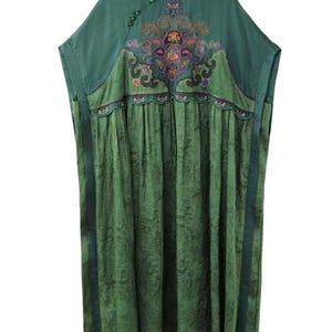 May include: A loose-fitting green tunic dress featuring a mandarin collar with small green buttons, short sleeves, and a textured skirt. The upper chest displays an intricate, multi-colored embroidered floral pattern with scalloped edges.