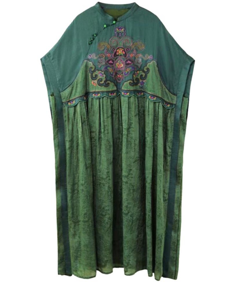 May include: A loose-fitting green tunic dress featuring a mandarin collar with small green buttons, short sleeves, and a textured skirt. The upper chest displays an intricate, multi-colored embroidered floral pattern with scalloped edges.