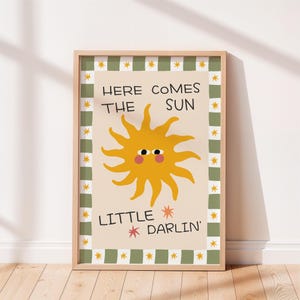 Puede incluir: Un cuadro enmarcado con una ilustración de un sol amarillo sonriente y el texto "HERE COMES THE SUN LITTLE DARLIN'". El borde es verde y blanco con estrellas. Una obra de arte alegre y soleada.