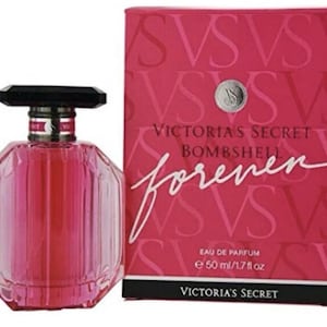 May include: A pink, faceted perfume bottle with a black cap and silver accents, next to a matching pink box. The box and bottle feature the text "Victoria's Secret Bombshell Forever". The bottle contains 1.7 fl oz (50 ml) of perfume.