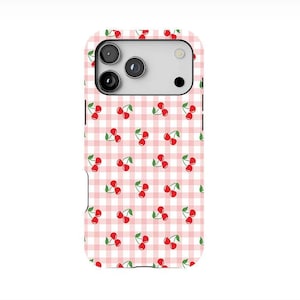 May include: A white and pink gingham patterned phone case with a repeating pattern of red cherries. The phone case has a camera cutout and is designed to fit a smartphone.