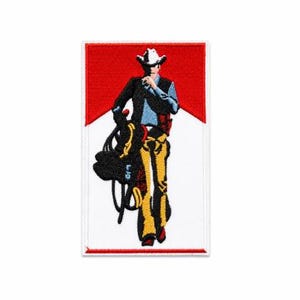 Puede incluir: Parche bordado con un vaquero con sombrero blanco, camisa azul y pantalones amarillos, sosteniendo una cuerda. El parche tiene un fondo rojo y blanco, con un borde blanco. El vaquero camina hacia adelante.
