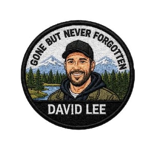 Puede incluir: Parche bordado circular con borde negro. Presenta un retrato de un hombre sonriente con gorra y chaqueta, con el texto "GONE BUT NEVER FORGOTTEN" y "DAVID LEE". El fondo muestra una escena de montaña y lago.