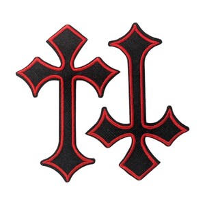 May include: Two embroidered patches in the shape of crosses. One cross is upright, and the other is inverted. Both patches feature a black centre with a bold red stitched border outlining the entire shape of the cross, creating a high contrast.