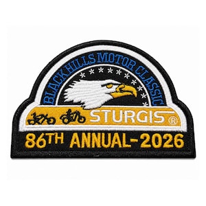 May include: A semi-circular embroidered patch featuring a white eagle head, the text BLACK HILLS MOTOR CLASSIC, and STURGIS. It includes silhouettes of two motorcycles, the text 86TH ANNUAL-2026 in yellow, and a border of white stars on black.
