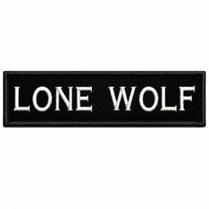 May include: A rectangular black embroidered patch featuring the white text LONE WOLF in a bold, capitalized serif font. The patch has a thick black border and a textured fabric surface, designed for attachment to clothing or other textile items.