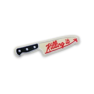 Puede incluir: Parche bordado con forma de cuchillo con mango negro y hoja color crema. El texto rojo "Killing it" está cosido en la hoja. El parche está sobre un fondo blanco.
