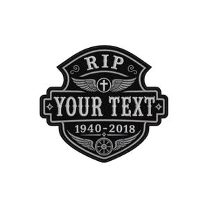 以下が含まれることがあります： 上部に「RIP」の文字が入った、白と黒の刺繍パッチ。パッチには翼のある十字架、「YOUR TEXT」の文字、そして「1940-2018」の日付が描かれています。パッチは装飾的な要素を持つ盾の形をしています。