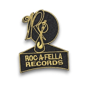 May include: Embroidered patch featuring the Roc-A-Fella Records logo. The patch has a black background with gold-colored embroidered details. The logo includes a stylized "R" and the text "ROC-A-FELLA RECORDS".