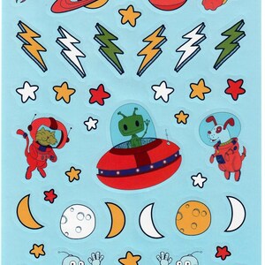 May include: A sheet of stickers with a light blue background featuring space-themed illustrations. Designs include planets, stars, lightning bolts, a cat and dog in spacesuits, an alien in a spaceship, robots, and crescent moons. The stickers are colorful and cartoon-like.