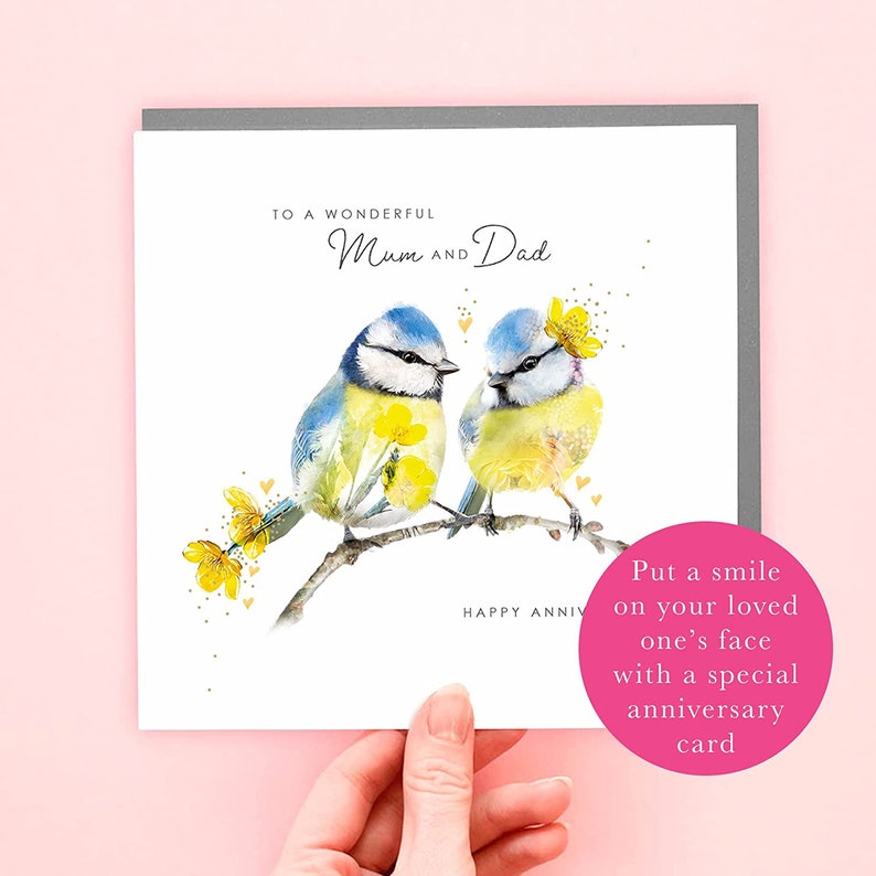 May include: A white card with a gray border features a watercolor illustration of two bluebirds perched on a branch with yellow flowers. The text "To a wonderful Mum and Dad" and "Happy Anniv" are printed on the card. The card also includes the text "Put a smile on your loved one's face with a special anniversary card."