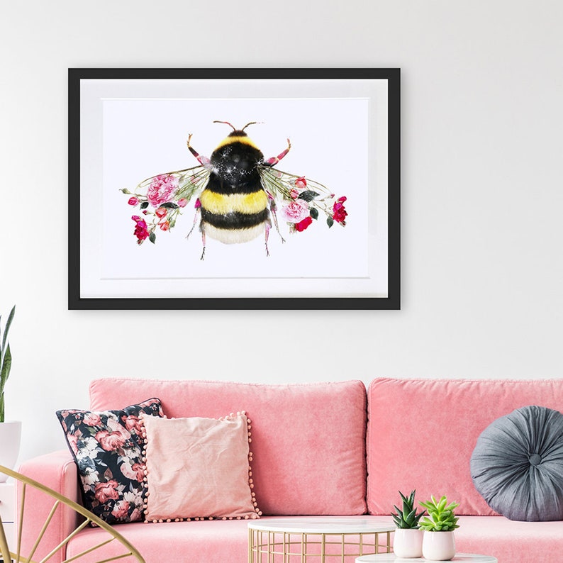 May include: A framed watercolor painting of a bumblebee with pink roses forming its wings. The bumblebee has a black and yellow striped body and a white background.