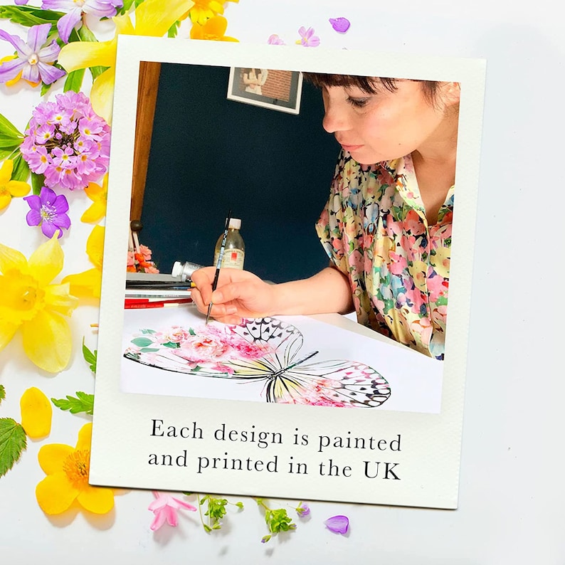 May include: A woman paints a watercolor butterfly design on a white sheet of paper. The butterfly is black and white with pink and yellow accents. The text "Each design is painted and printed in the UK" is at the bottom of the image.