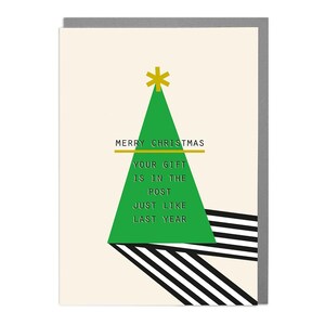 May include: A Christmas card with a green geometric Christmas tree design and the text "MERRY CHRISTMAS YOUR GIFT IS IN THE POST JUST LIKE LAST YEAR". The card has a cream background and a gray border.