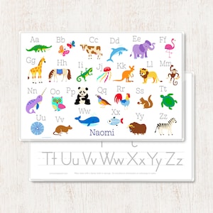 May include: A white wipe-clean alphabet chart with colorful illustrations of animals for each letter. The chart includes the letters A through Z and the name "Naomi" at the bottom. The chart also includes a practice area for writing the letters T, U, V, W, X, Y, and Z.