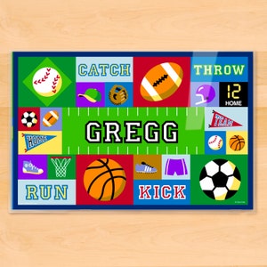 Sports place mat for kids. Child name in center on a green sports field in traditional letter men font, surrounded by colorful sports ball, and equipment.