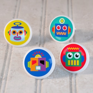 May include: Four colorful ceramic knobs with robot faces. The knobs are yellow, blue, red, and green. Each knob has a different robot face with unique features.