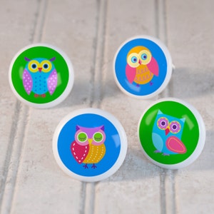 May include: Four colorful ceramic owl knobs with different designs. Each knob features a different owl with bright colors and patterns. The knobs are perfect for adding a whimsical touch to any room.