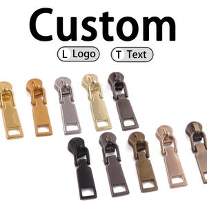 Puede incluir: Una colección de tiradores de cremallera metálicos en varios colores, incluyendo dorado, plateado y negro. La palabra "Custom" se muestra encima de los tiradores, con opciones para "L Logo" y "T Text".