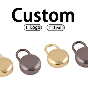 Puede incluir: Cuatro cierres redondos de metal con asa de bucle en colores dorado y plomo. La palabra "Custom" está encima de los cierres, con opciones para un logotipo o texto.