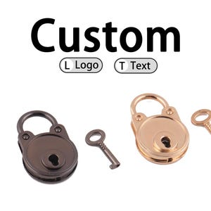Puede incluir: Dos candados decorativos con llaves. Uno es marrón oscuro, el otro dorado. La palabra "Custom" está encima de los candados, con opciones para "L Logo" y "T Text".