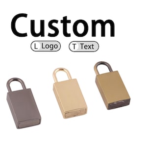 Puede incluir: Tres pequeños candados rectangulares en diferentes acabados metálicos: metal de cañón, dorado y latón. La palabra "Custom" está encima de los candados, con opciones para "L Logo" y "T Text".