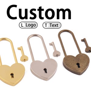 Puede incluir: Candados en forma de corazón en oro, plata y bronce con llaves a juego. Los candados tienen un diseño clásico con un ojo de cerradura y un asa curvada. La palabra "Custom" se muestra encima de los candados.