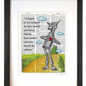 Puede incluir: Una impresión enmarcada de una página de libro vintage con una ilustración dibujada a mano del Hombre de Hojalata de El Mago de Oz. El Hombre de Hojalata camina por un camino de ladrillos amarillos con un corazón rojo en el pecho. La cita "Un corazón no se juzga por cuánto amas: sino por cuánto eres amado por los demás." está impresa en la página.