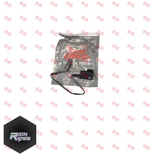 May include: A black Royal Enfield genuine parts electrical component, with wires and a connector, is shown on a white background. The component is packaged in a clear plastic bag with the Royal Enfield logo and text.