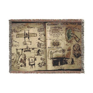 Puede incluir: Manta tejida con un diseño vintage estilo cuaderno de bocetos. La manta beige presenta dibujos de un avión, figuras y texto que incluye "Remember This All Don't Forget" y "Escape Plan". Los bordes tienen un ribete de flecos.