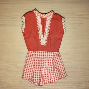 May include: Red and white gingham doll dress with white lace trim around the neckline and armholes.