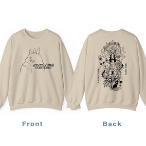 May include: Beige sweatshirt with a black and white Studio Ghibli character illustration on the front. The back showcases a detailed graphic of various characters from the studio. The text "STUDIO GHIBLI" is printed on the front and back of the sweatshirt.