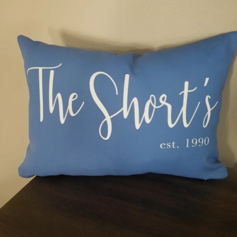 20 by 14 inch lumbar throw pillow personalized with your last name and established year in a fancy script font. Choice of text and background colors. Design is printed on both sides of pillow.