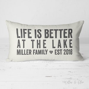 May include: A white throw pillow with black text that reads "Life is better at the lake Miller Family Est 2018".