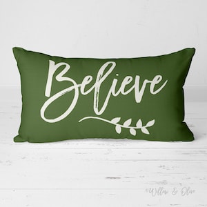 20 by 14 inch lumbar throw pillow with the text Believe accented with a leaf sprig in choice of Christmas Red or Pine Green Colors. Design is printed on both sides of pillow.