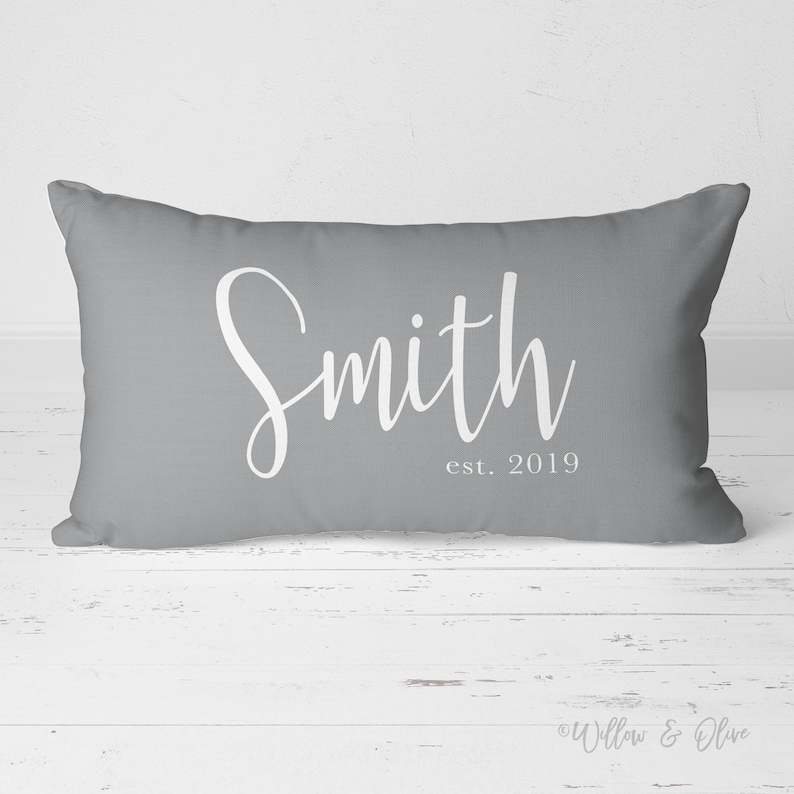 20 by 14 inch lumbar throw pillow personalized with your last name and established year in a fancy script font. Choice of text and background colors. Design is printed on both sides of pillow.