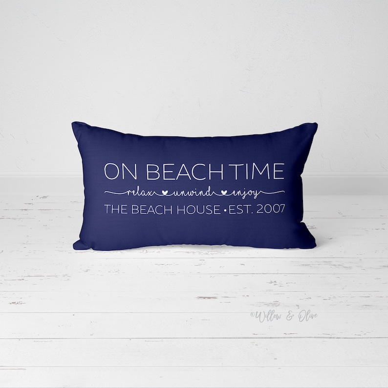 Puede incluir: Coj&iacute;n de color azul marino con texto blanco que dice "ON BEACH TIME relax unwind enjoy THE BEACH HOUSE EST. 2007".