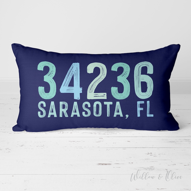May include: A navy blue cushion with white text that reads "34236 Sarasota, FL" in a blue and green gradient.