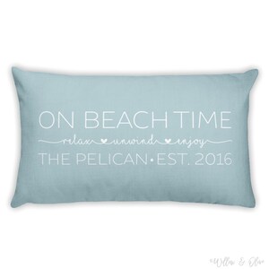 Beach house pillow with quote On Beach Time on first line, then relax, unwind, enjoy on second line in script font. Third line is personalized with your beach house name or family name and established year. Choice of colors for both font and pillow.