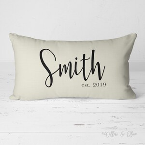 20 by 14 inch lumbar throw pillow personalized with your last name and established year in a fancy script font. Choice of text and background colors. Design is printed on both sides of pillow.