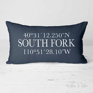 May include: A navy blue pillow with white text that reads "40°31′12.250″N SOUTH FORK 110°51′28.10″W".