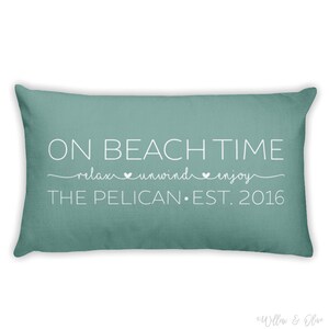 Beach house pillow with quote On Beach Time on first line, then relax, unwind, enjoy on second line in script font. Third line is personalized with your beach house name or family name and established year. Choice of colors for both font and pillow.