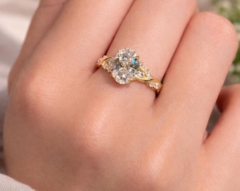 May include: A gold engagement ring with a large oval-cut diamond center stone. The band features a twisted design with smaller accent diamonds. The ring is set in a gold band and is shown on a person's finger.
