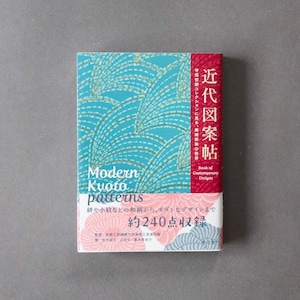 May include: A rectangular book titled Modern Kyoto Patterns with a teal cover featuring gold wave motifs, a red vertical spine section with white Japanese text, and a bottom section displaying pink and grey floral patterns with text.